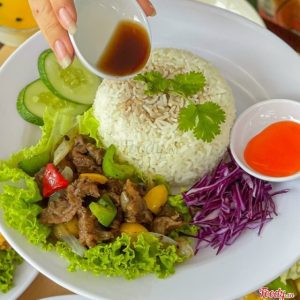Đĩa cơm bò sốt tiêu đen xào ớt chuông ăn kèm rau sống và nước tương
